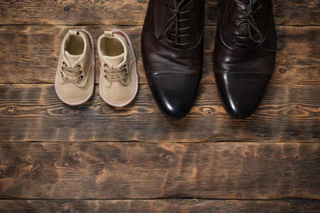 Baby and father shoes on the wooden floor flat lay background with copy space.の写真素材