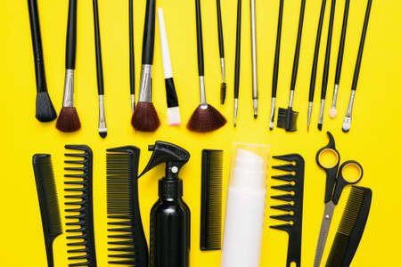 Makeup brushes, scissors and hairbrushes on the yellow flat lay background.の写真素材