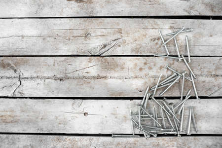 Pile of nails on the old white wooden workbench background with copy space.
