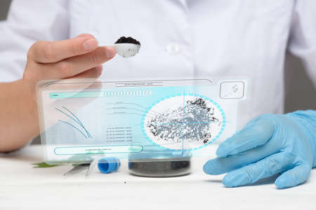 Soil samples analysing concept. Scientist with a sample of soil and digital tablet with researching...