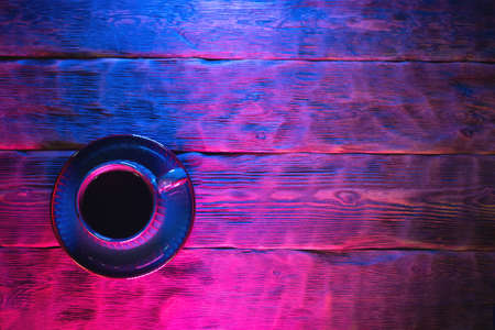Coffee cup on the wooden table background in neon lights.の写真素材