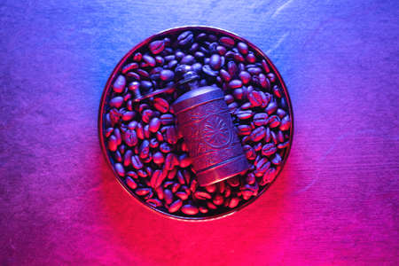 Coffee beans on the plate in the neon lights top view background.