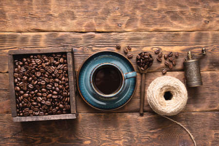 Coffee cup and coffee beans in the wooden container box on the table.