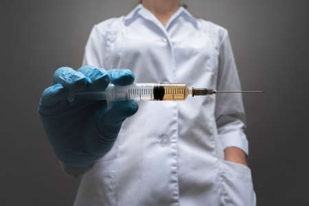 A syringe with medicine in doctor hands close up.の写真素材