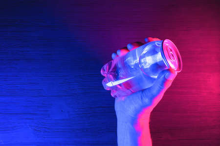 A transparent soda can in the neon lights on the black table background.の写真素材