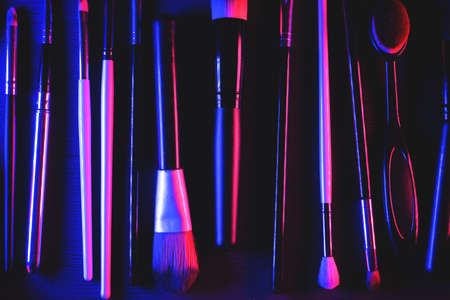 Make up brushes on the flat lay table background in the neon color lights.の写真素材