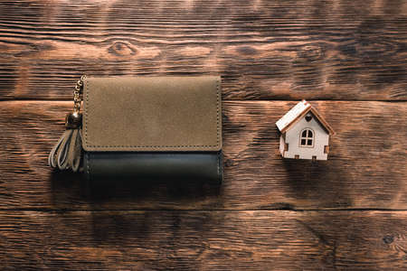 Small house and wallet on the wooden table background. Buy house.