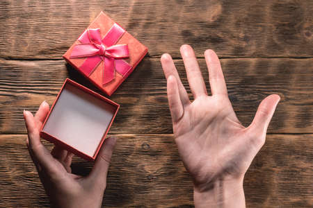 An open empty gift box and female hands on the wooden table background. No gift concept.の写真素材