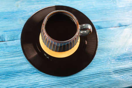 A black coffee in the cup and vinyl record on the blue table background.の写真素材