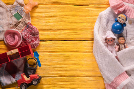 Old children toys and girl sweater on the wooden flat lay floor background.