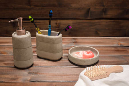 Bath accessories, soap dispenser, comb and toothbrush on the wooden table background. Hygiene.