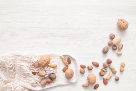 String bag and various kinds of nuts on the white wooden table background with copy space.の写真素材