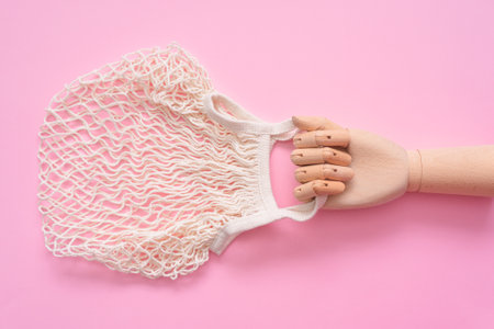 String bag in the toy wooden hand on the pink background.の写真素材