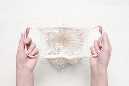 Empty string bag in the female hands on the white wooden table background.の写真素材