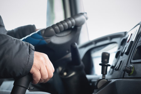 Truck driver hands on the steering wheel of the car close up.