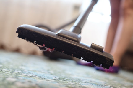 Woman is cleaning the floor by the vacuum cleaner close up.の写真素材