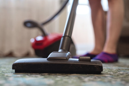 Woman is cleaning the floor by the vacuum cleaner close up.の写真素材