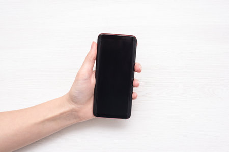 A blank screen mobile phone in the female hands on the white background.の写真素材