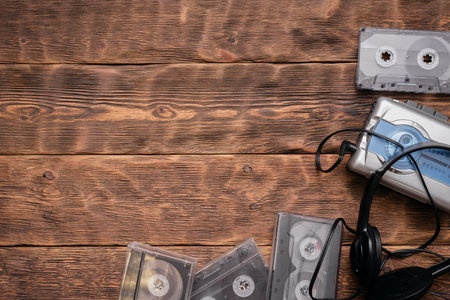Portable retro stereo cassette player, old headphones and cassettes ont he brown wooden table background.の写真素材