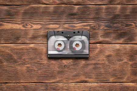 Old retro cassette on the brown wooden table background.の写真素材
