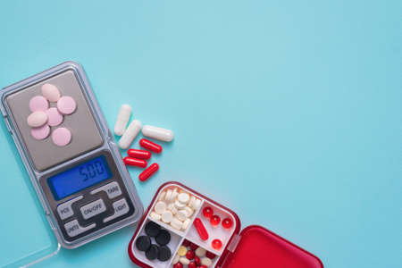 Medical pills assortment and digital weights on the blue background.