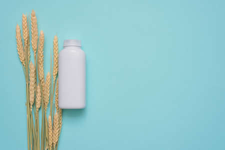 Wheat product in the jar and wheat stems on the blue background.の写真素材