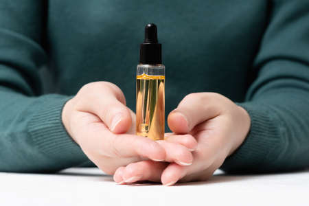 Woman is showing a bottle of cuticle oil close up. Finger nail care.の写真素材