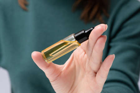Woman is showing a bottle of cuticle oil close up. Finger nail care.の写真素材