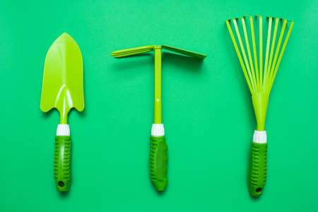 Gardening tools abstract flat lay background. Rake, spade and hoe on the green background top view.