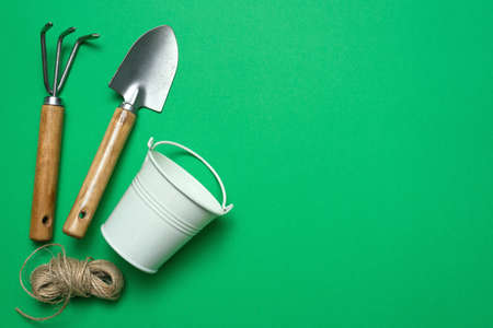 Garden tools on the green background with copy space. Rake, spade, jute rope and small water bucket.の写真素材