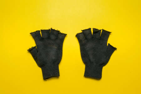 Pair of black construction gloves isolated on the yellow background.