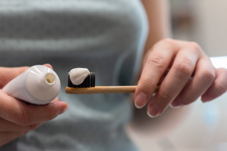 Woman will squeeze the toothpaste from the tube onto the toothbrush close up.の写真素材