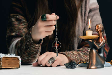 Fortune teller with a magic pendulum in the hands close up concept.の写真素材