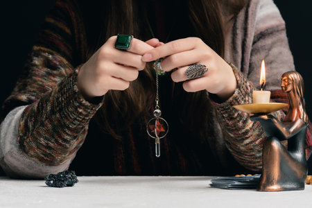 Fortune teller with a magic pendulum in the hands close up concept.