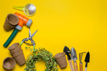 Gardening tools and flower pots with a soil on the yellow flat lay background with copy space....