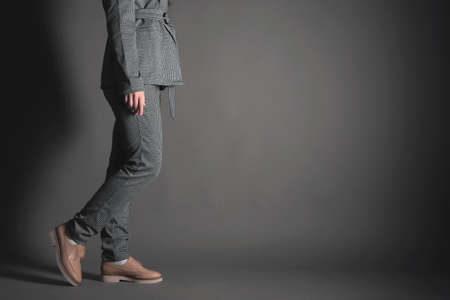 Woman in the gray suit and shoes steps on the gray background with copy space. Side view.の写真素材