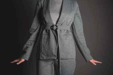 Woman in the gray suit is posing on the gray background.