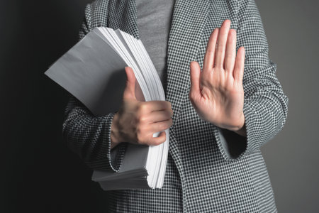 Office worker is showing a stop gesture sign by her hand on the gray background.の写真素材