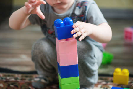 A little boy is playing with a children building kit close up.