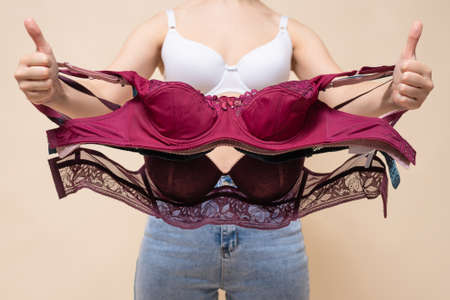 Woman a customer is choosing a new bra in a lingerie store and is showing a thumbs up gesture concept.の写真素材