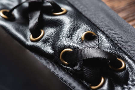 Strings lace close up on the black leather clothes abstract background.