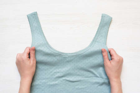 Women hands is holding in hands a mint color shirt on the white store counter background.の写真素材