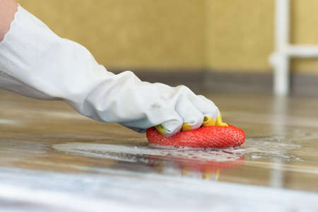 Woman hand is mopping a floor by the sponge and laundry soap.