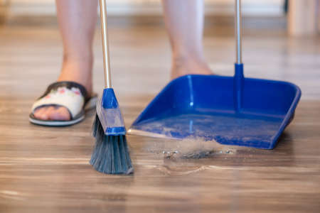 Broom brush and dustpan on the floor. Home cleaning.