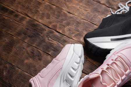 A high sole female sneakers on the brown wooden floor background with copy space.