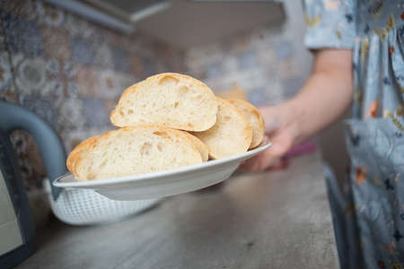 Woman holds a sliced piece of loaf on the plate close up.