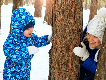 Happy and joyful mother and child on walk, play in the winter forest. Pine forest of Chelyabinsk region, Ural, Russia. Family portrait.の写真素材