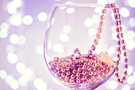 Festive card ornament golden decor in wine glass against sparkling bokeh of holiday party light. Christmas concept congratulation New Year.の写真素材