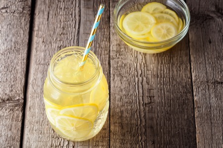 Coctail jar of lemonade and ice cubes crumbs on a wooden table backgroundの写真素材