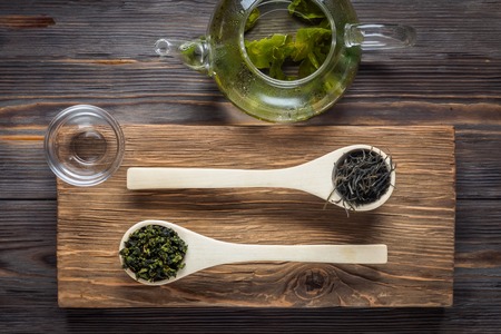 Traditional Chinese green tea different fermentation wooden culinary spoons teapot with fresh brewed leaves on dark table low key food concept top view Wabi Sabi lifestyle.の写真素材